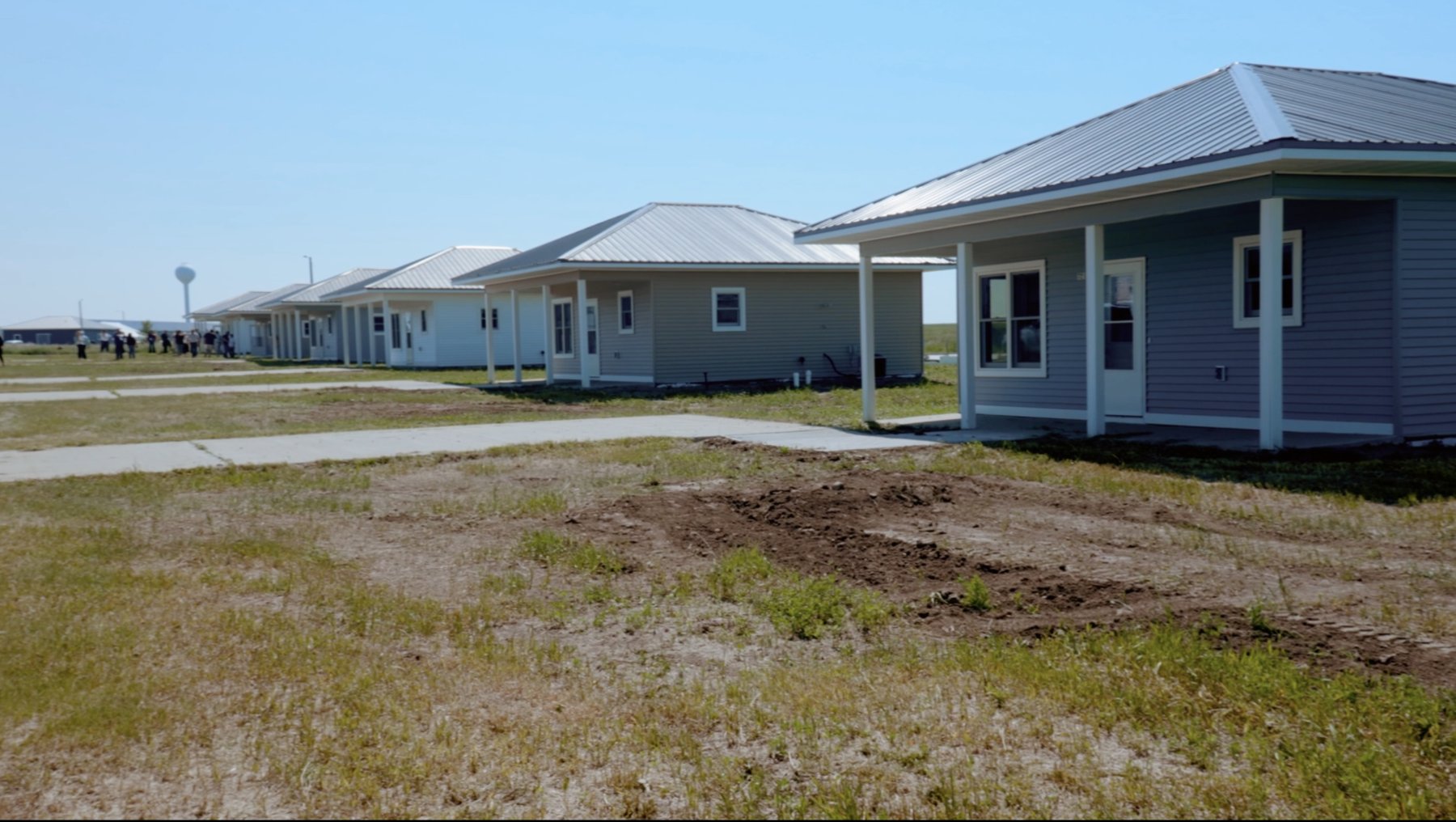 A row of newly built Tribal housing homes with covered porches on open prairie